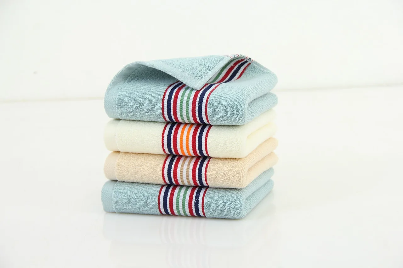 Three microfiber towels on a garage workbench beside a car hood in natural light