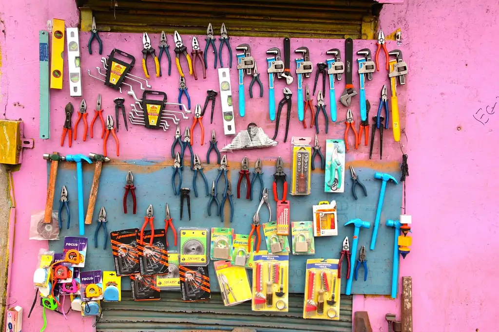 Three panel clip pliers beside a car door trim panel and plastic fasteners on a garage workbench