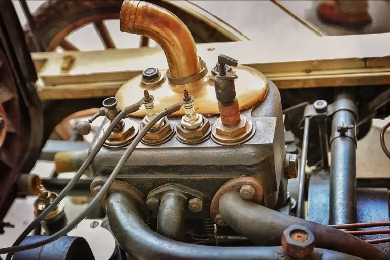 Three performance spark plugs beside a cylinder head on a mechanic’s workbench