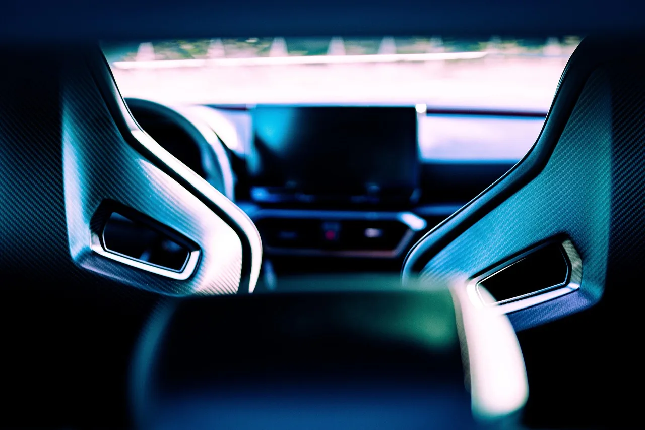 Driver in a racing seat inside a stripped sports car cockpit with natural light