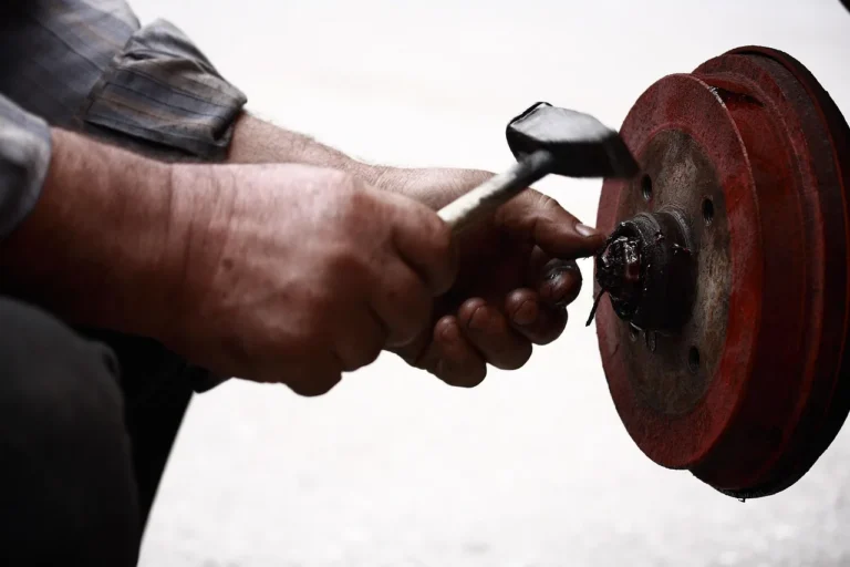 Mechanic applying rust inhibitor under a car on a lift in a garage