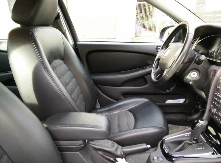 Detailer wiping a tan leather car seat with a microfiber cloth in natural light