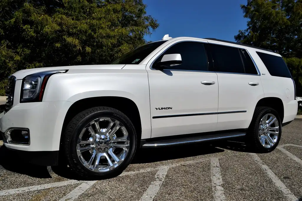 Midsize SUV beside four all-season tires on a driveway with a mechanic checking tread depth