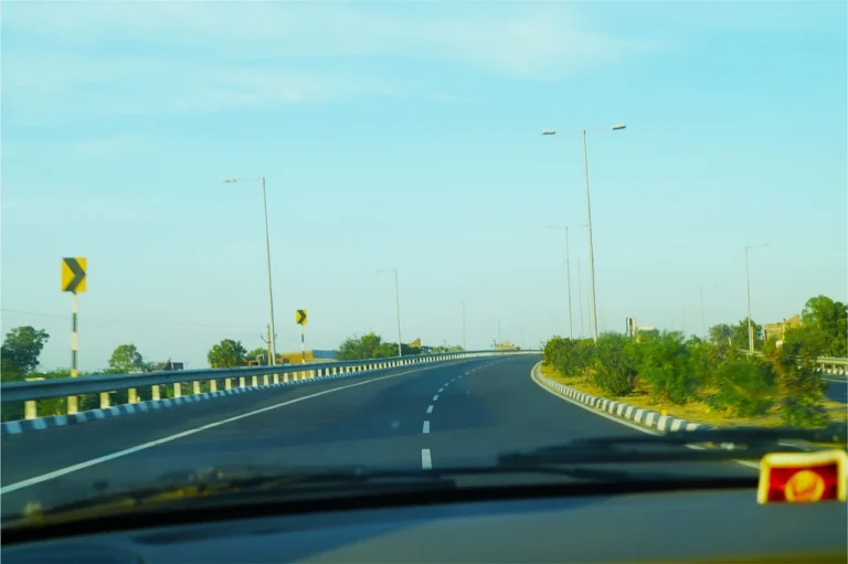 BlackVue dash cam mounted behind a rearview mirror inside a car with a city street ahead