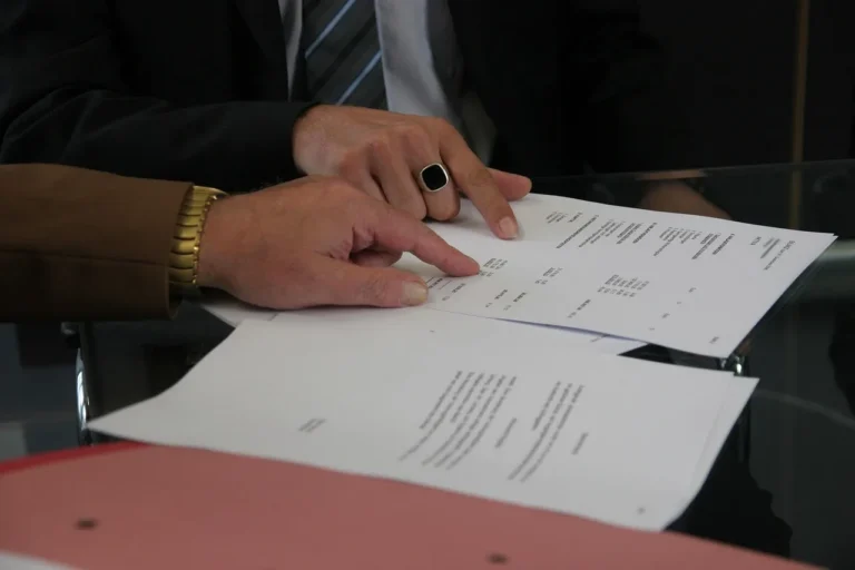 Buyer and salesperson reviewing car loan paperwork beside keys and calculator in a dealership office.
