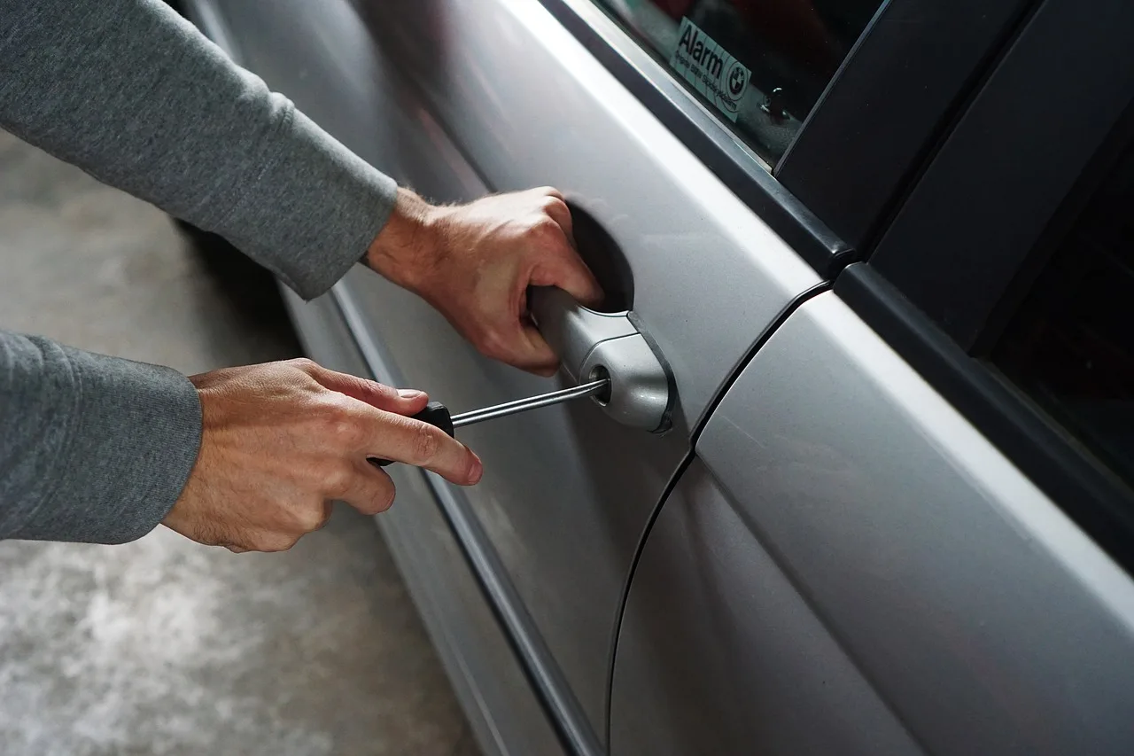 Car lockout service cost scene with a locksmith opening a sedan for a stranded driver.