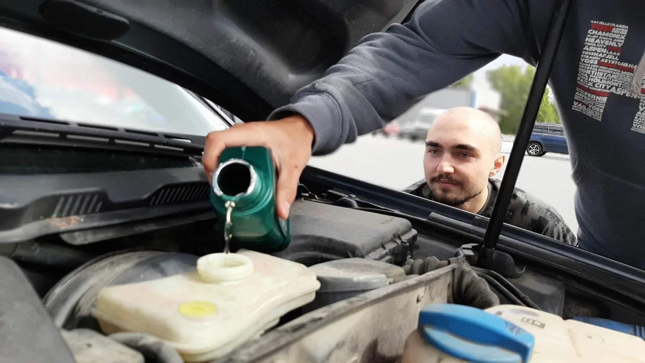 Busy professional checks tire pressure beside a modern sedan in a sunlit driveway.