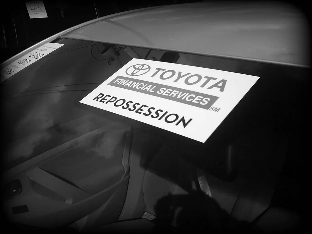 Repossession notice, car key fob, and gate latch on a driveway entrance