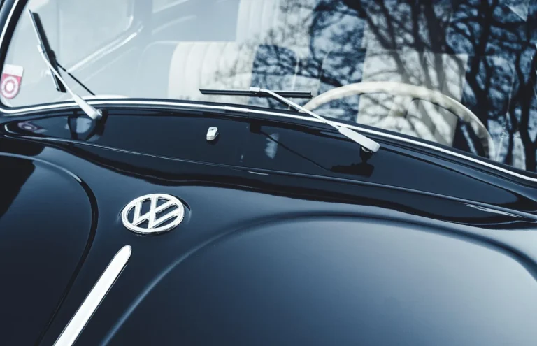 Car window repair cost estimate beside a car with a chipped driver-side window in a service bay