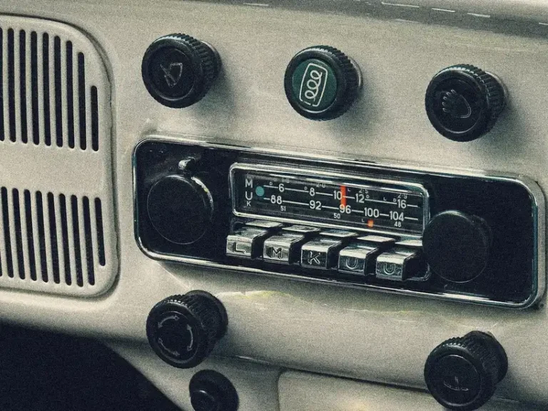CB radio installed in a car dashboard with a hand reaching for the microphone