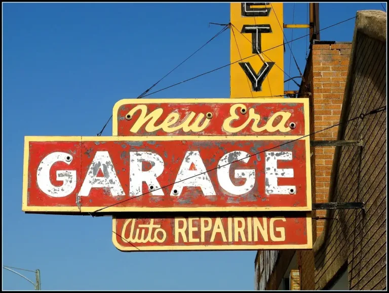 Car owner and mechanic reviewing service items beside a sedan at a neighborhood auto shop