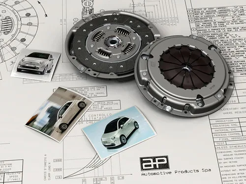 Worn clutch disc beside a new pressure plate and release bearing on a bench