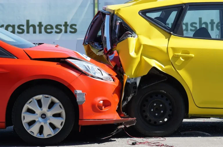A driver reviews insurance paperwork beside a compact sedan in a sunny driveway.