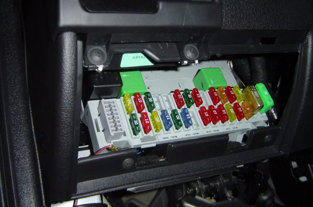 Driver compares a dash cam hardwire kit and cigarette lighter plug beside a parked sedan