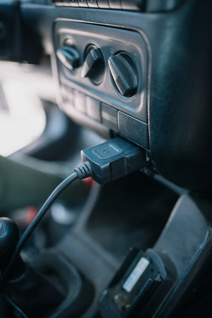 Mechanic uses a scan tool connected to a car's OBD-II port.