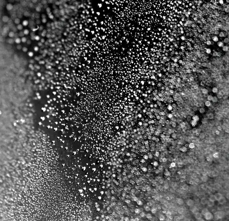 Hand misting detailing spray onto a microfiber towel over a glossy car panel