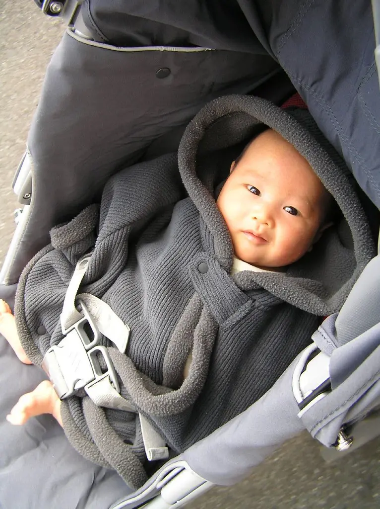Hands securing a Doona car seat into a car base in the back seat