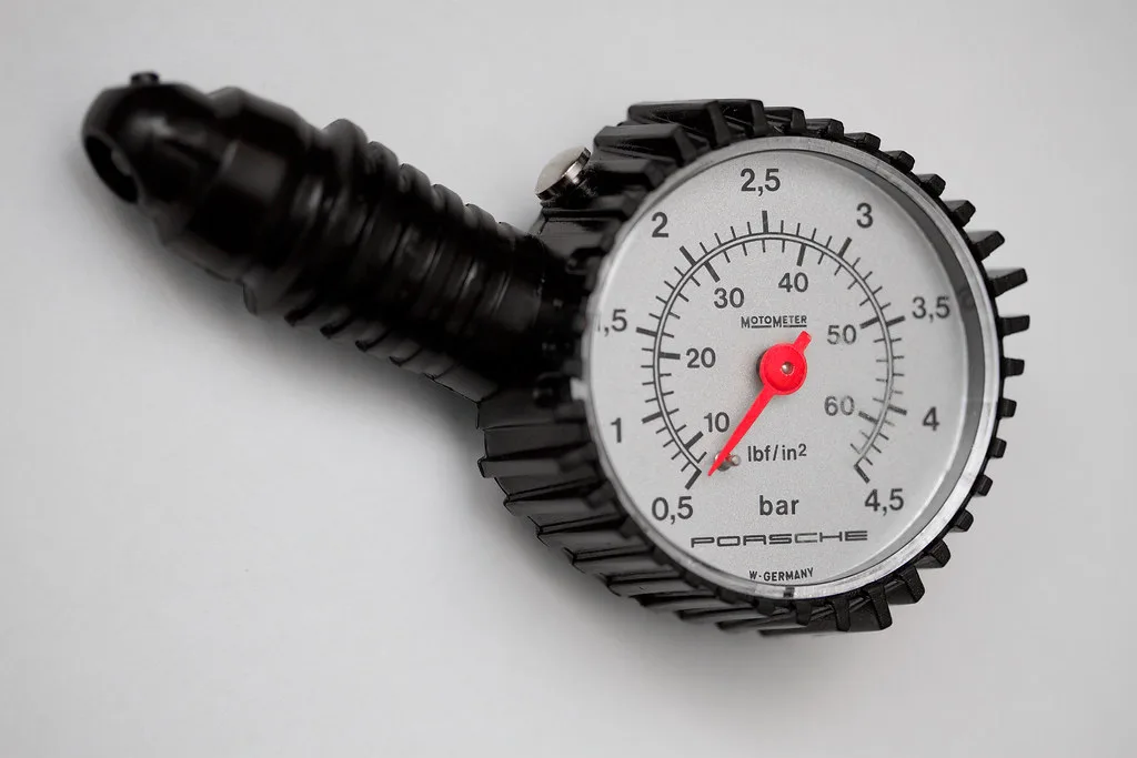 Close-up of a hand using a tire pressure gauge on a car tire valve