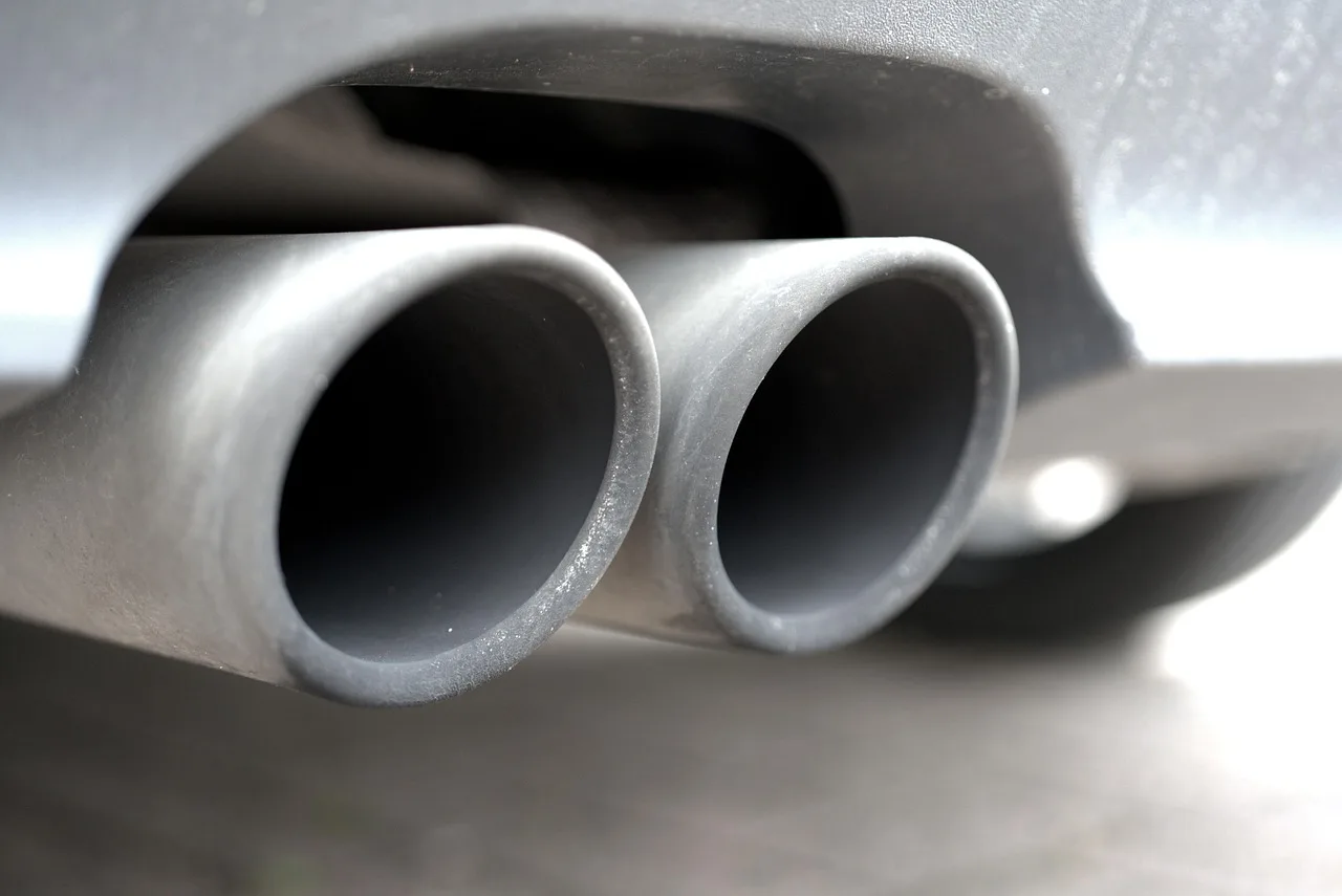 Driver beside a sedan at a state inspection station for an emissions test vs vehicle inspection