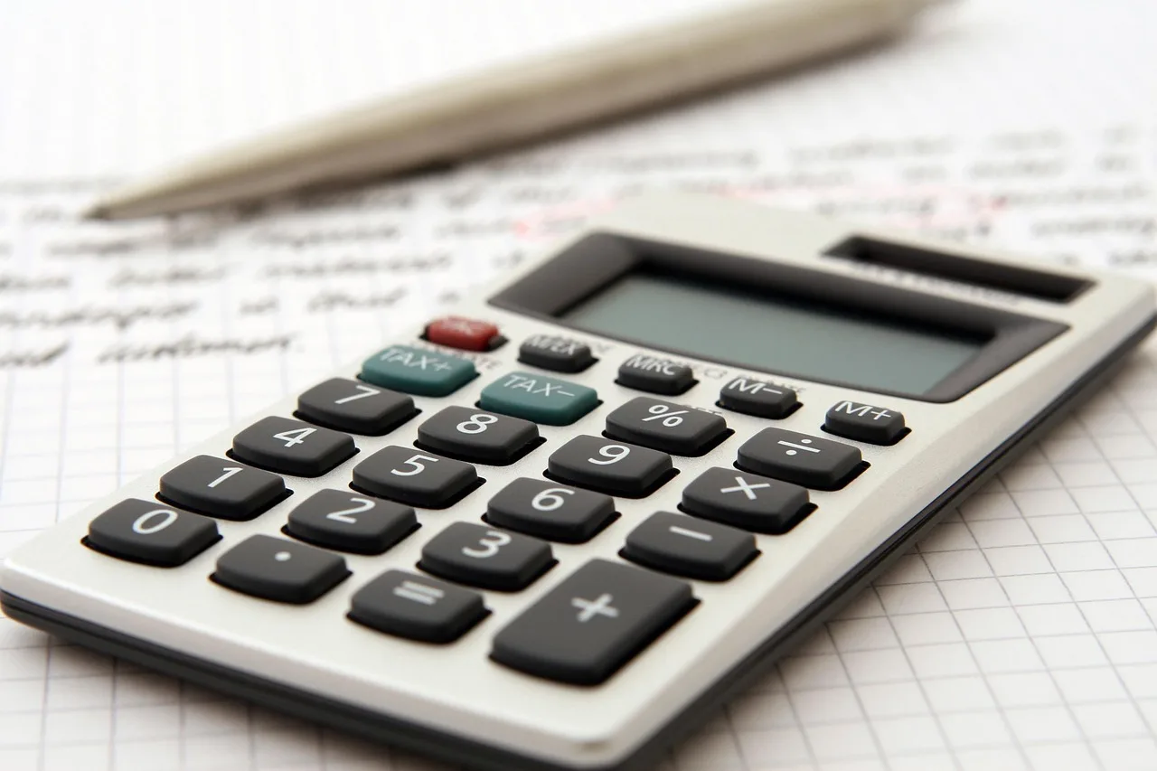 A concerned driver reviews car lease paperwork and a calculator at a kitchen table.