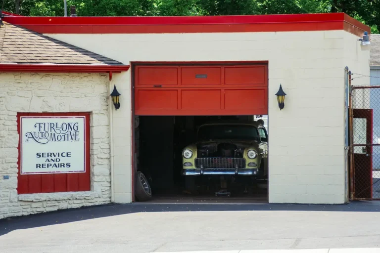 A mechanic inspects an aging sedan with the hood open in a driveway, showing Endurance Car Repair Insurance Review context.