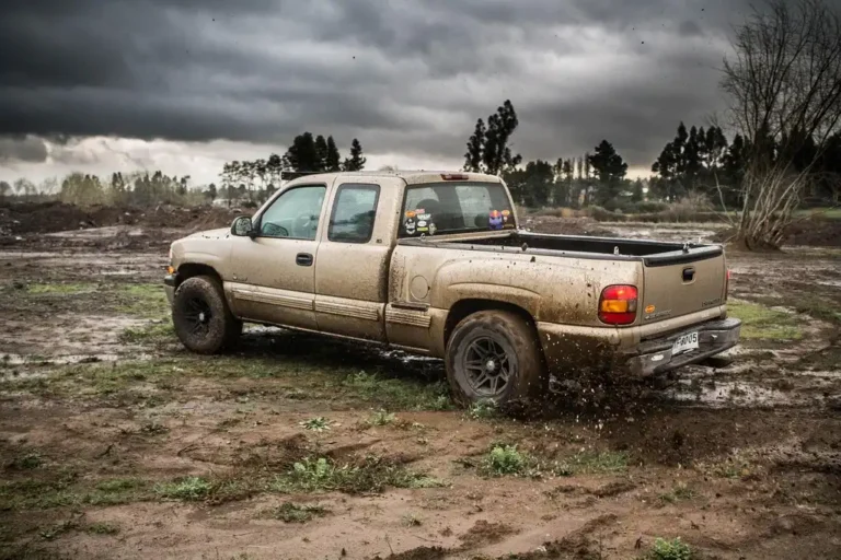 Chevy Silverado on a wet gravel road in 4-High with spray behind the tires