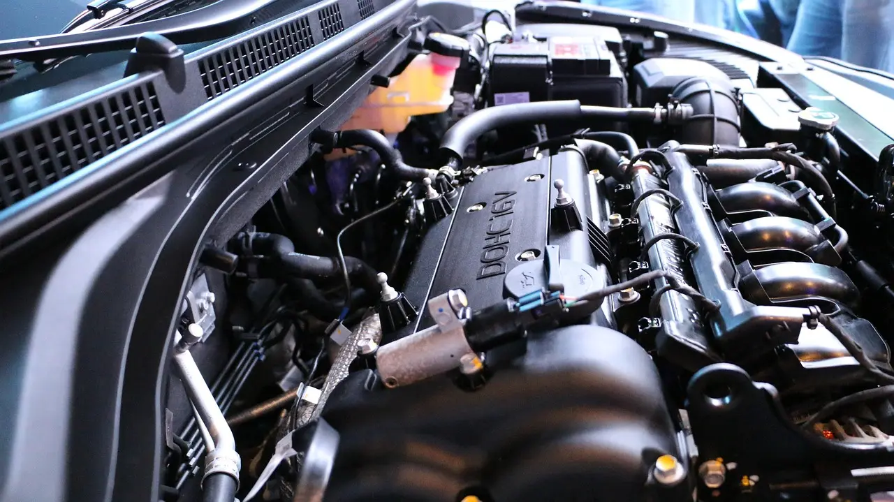 Mechanic installing a remote start module under a car dashboard in a shop