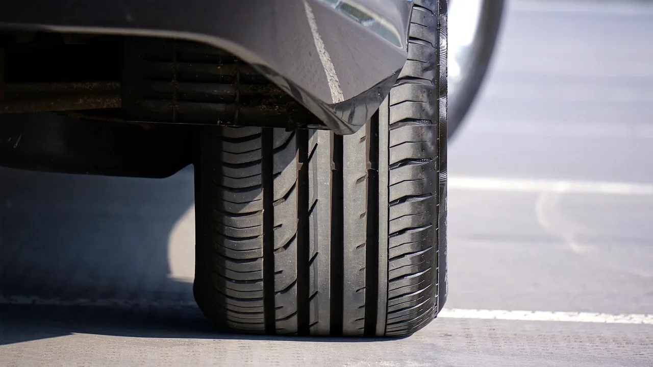 A compact sedan drives on a wet road in cold mixed weather with slush at the curb for Goodyear Assurance WeatherReady Review.