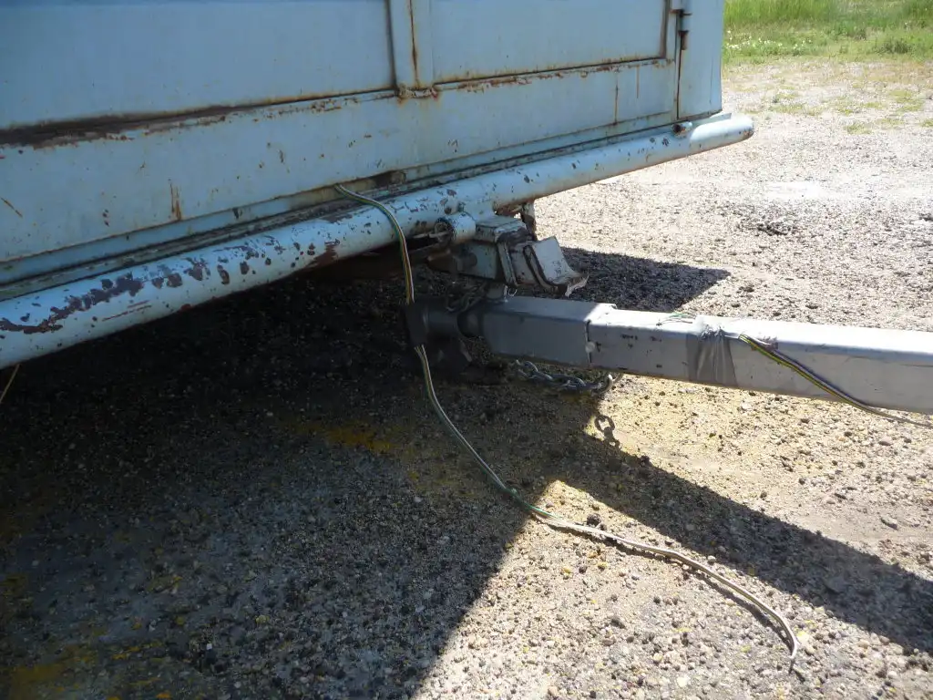 Close-up of a trailer hitch, safety chains, and camper tongue weight setup.