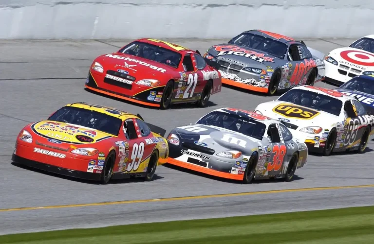 NASCAR stock car racing past the grandstands on an oval track at speed