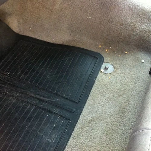 Hands use a calculator beside loan papers and a car key fob to estimate monthly car cost.