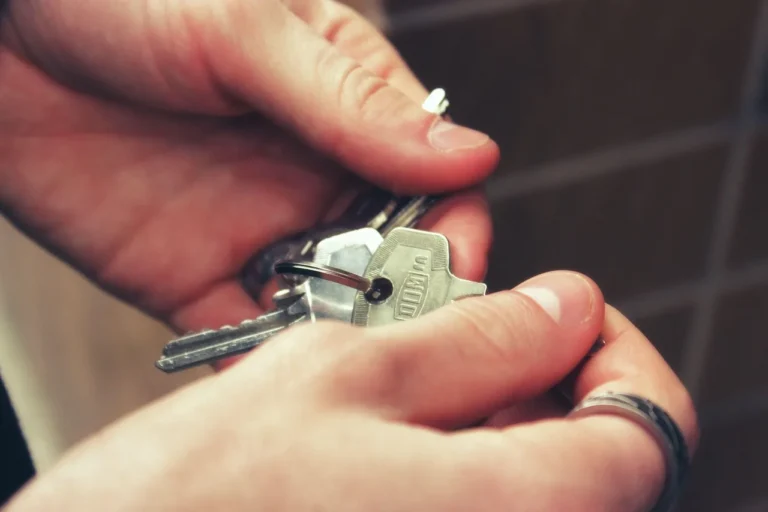 Traveler beside a rental car at a UK airport car park with keys and a price breakdown in hand