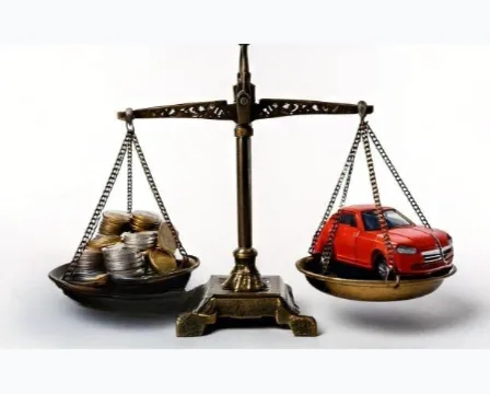 Hands with calculator beside car valuation papers and insurance documents