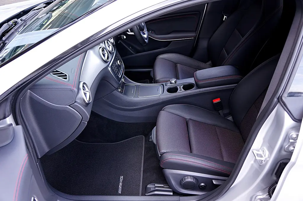 Car owner reviews leather seat care supplies beside a premium leather car interior.