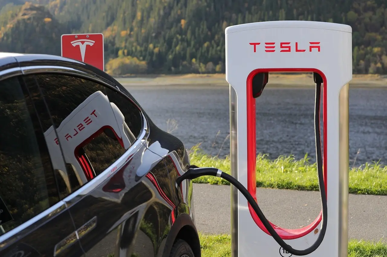 Tesla cars parked outside a home with a person comparing a price sheet