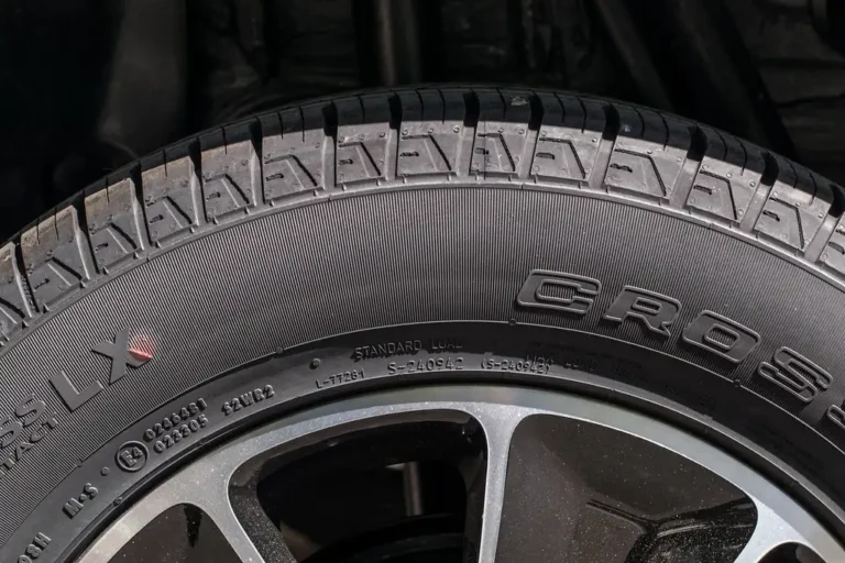 Mechanic and car owner reviewing a wheel alignment estimate beside a lifted sedan