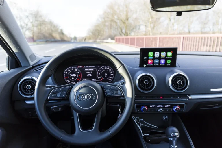Audi car interior with steering wheel, dashboard screen, and road ahead through the windshield