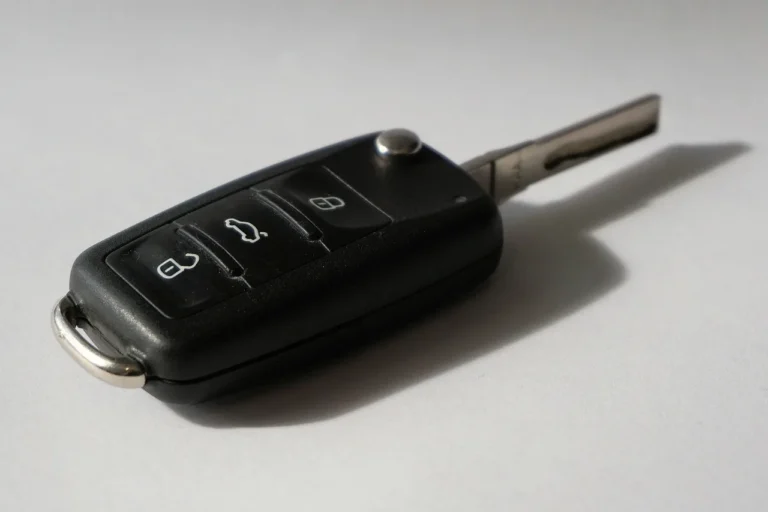 Honda car owner and locksmith reviewing a key fob and metal key blank beside a parked sedan