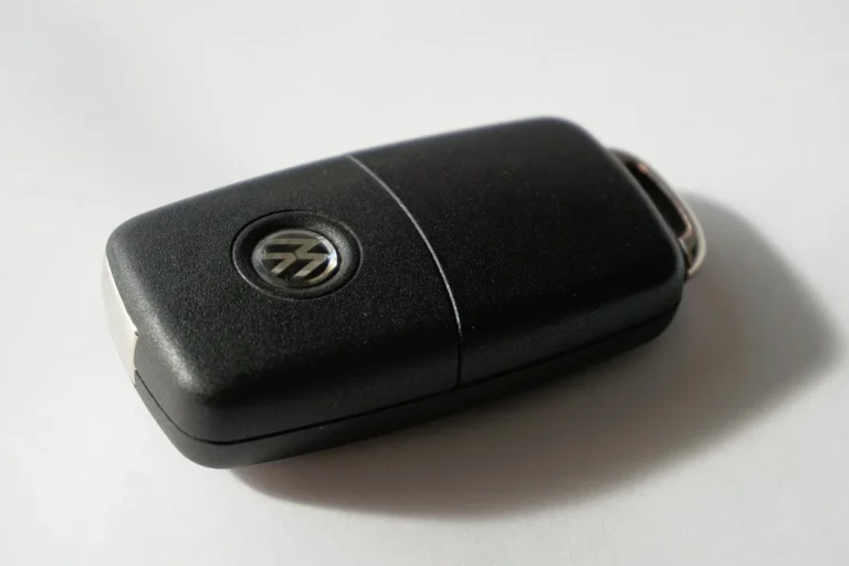 BMW owner using a key fob beside the rear trunk of a parked sedan