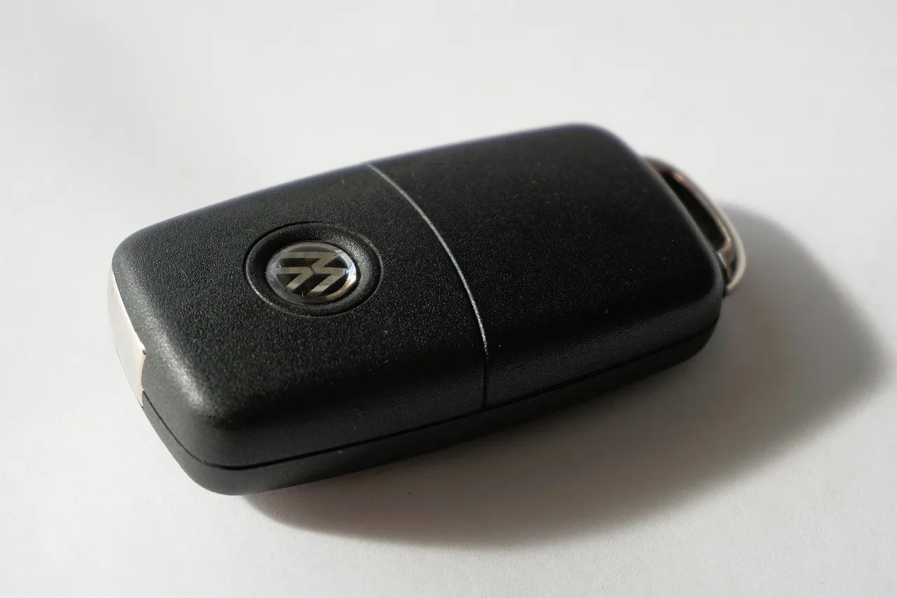 BMW owner using a key fob beside the rear trunk of a parked sedan