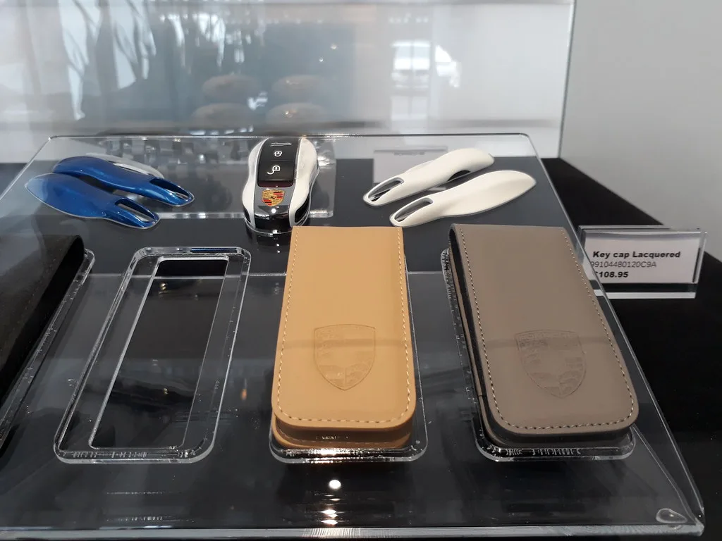 Hand pressing the trunk-release button on a BMW key fob near a car