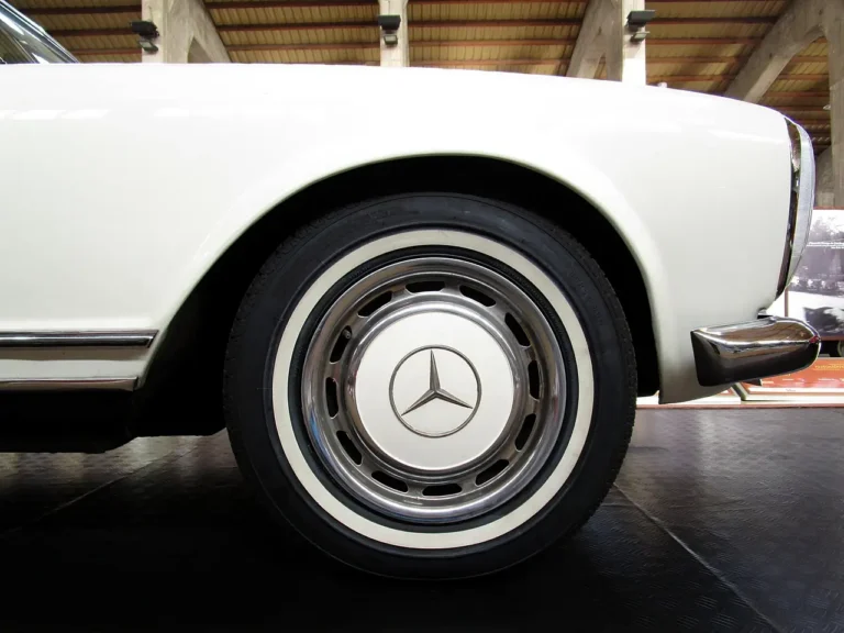Close-up of a white Mercedes car wheel indoors on a showroom floor