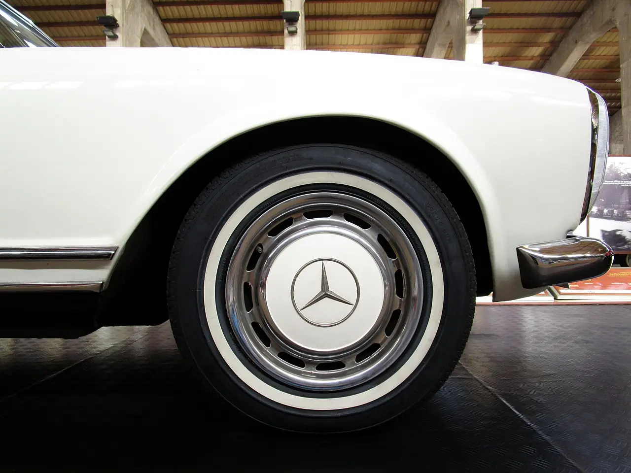 Close-up of a white Mercedes car wheel indoors on a showroom floor
