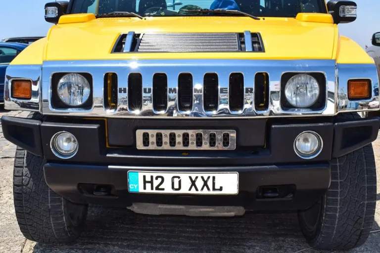 A Hummer-style SUV parked on a suburban street with a driver loading gear nearby