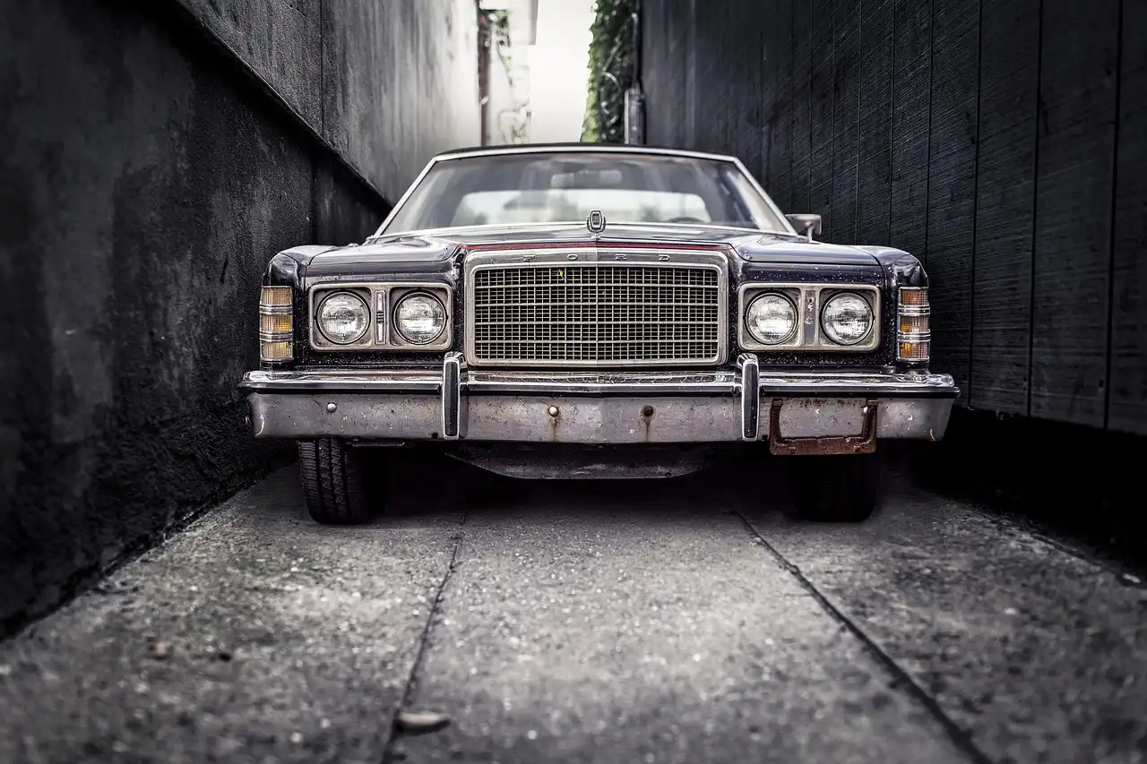 Front view of a vintage Ford car parked in a narrow alley