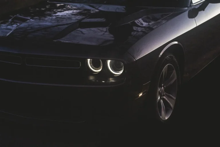 JDM ASTAR LED headlight bulbs beside an open headlight housing in a garage