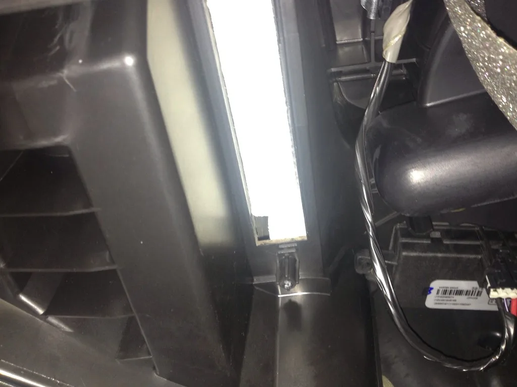 Hands rinse a K&N cabin air filter under water during cleaning