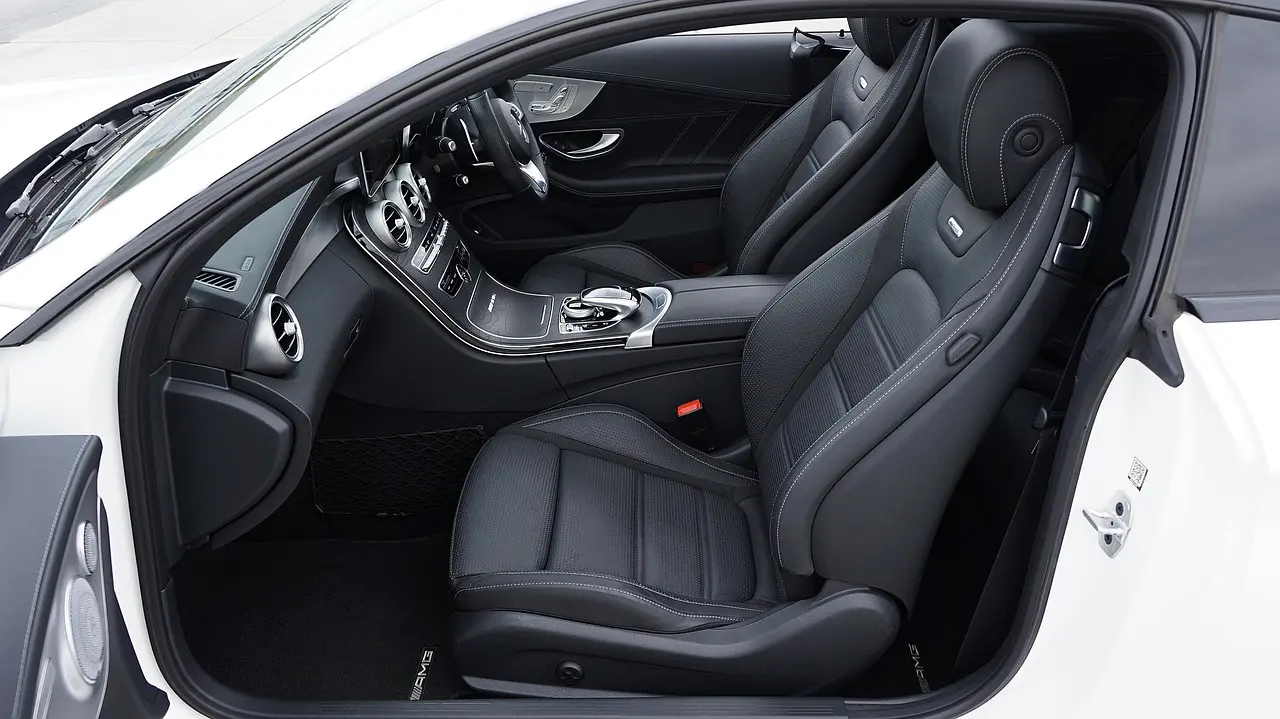 Leather car seat beside cleaner bottles and microfiber cloths in natural light