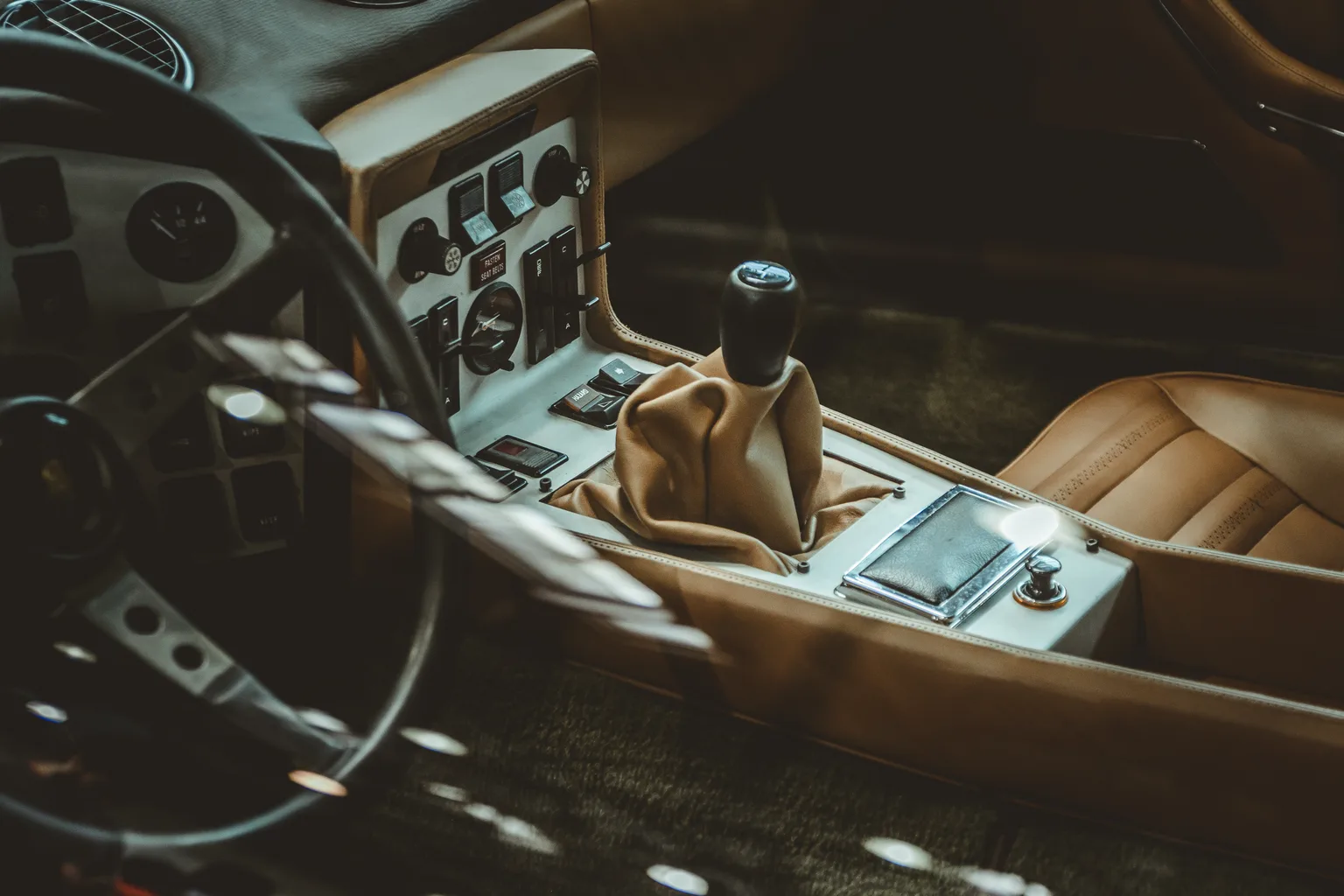 Auto detailer cleaning a tan leather car seat in natural light