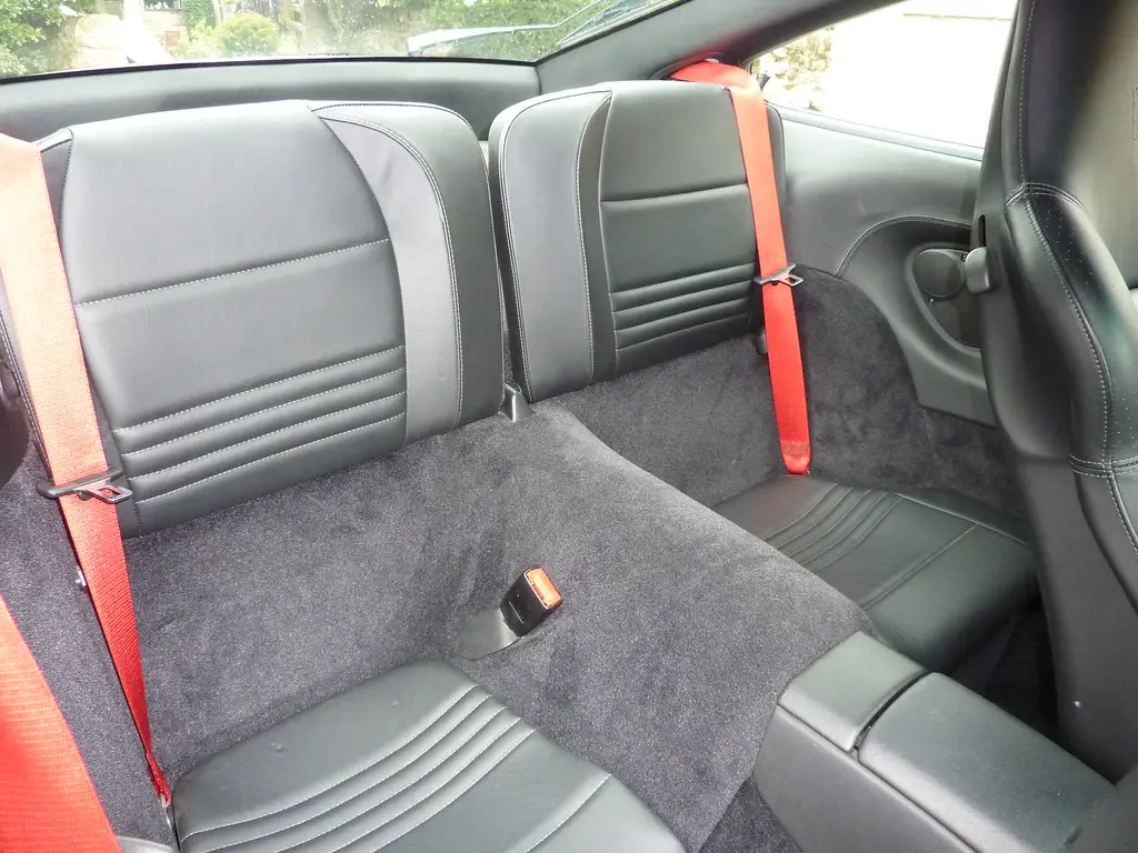 Microfiber cloth cleaning a perforated leather car seat with spray cleaner